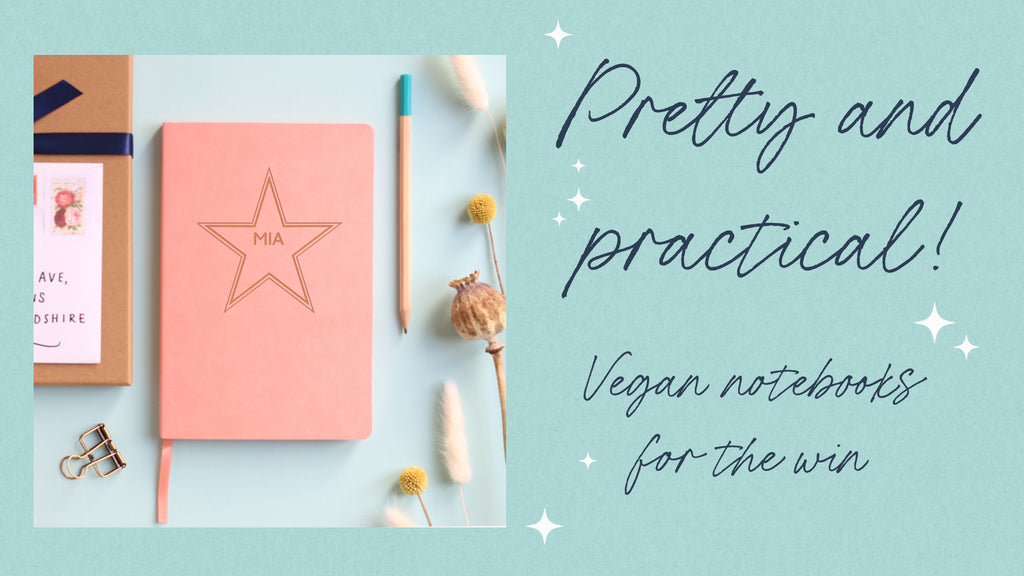 A pink vegan leather notebook with a large star in the middle and the name "Mia" engraved in the middle of the star. Styled on a duck egg blue background with pencil, paper clip and dried flowers around.