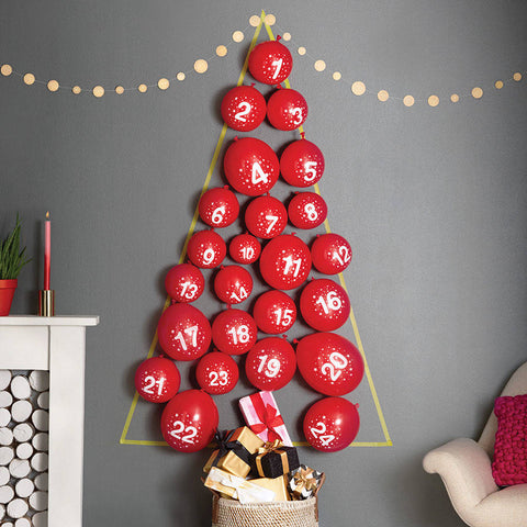 red balloons, numbered in white 1-24, are inflated and stuck to a grey wall in the shape of a Christmas Tree.