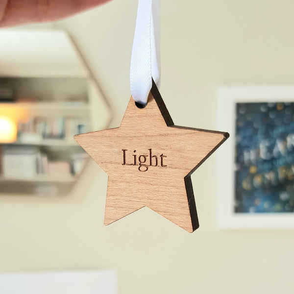 Inspirational word of the year wooden star being held by white ribbon, engraved with the word "light"