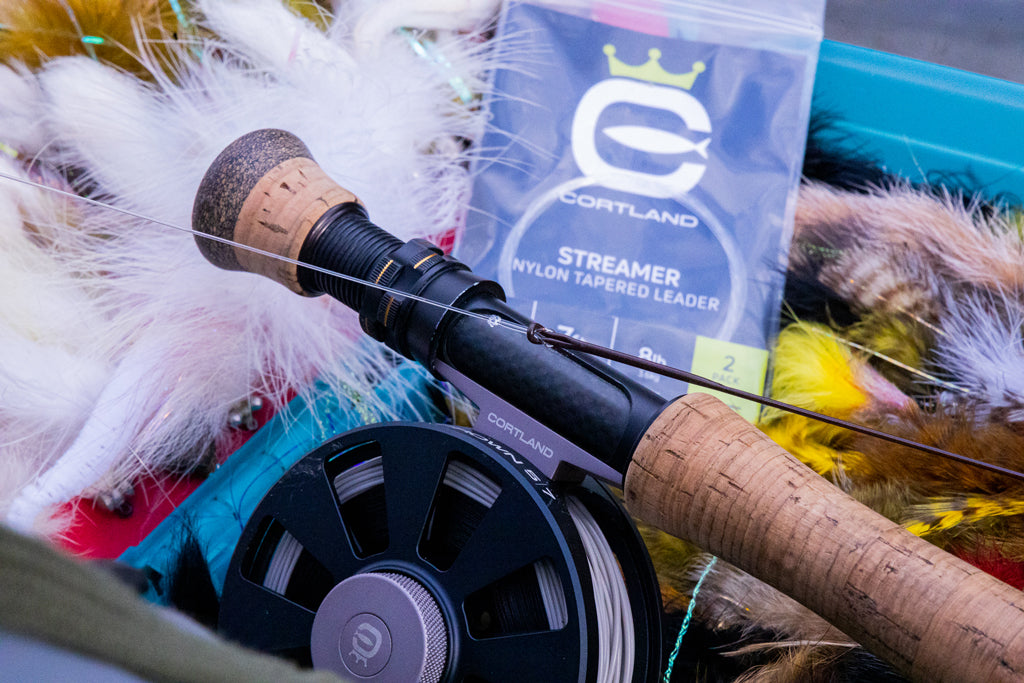 Fliegenrolle mit verschiedenen Fliegen und Streamer Nylon Tapered Leader in der Verpackung