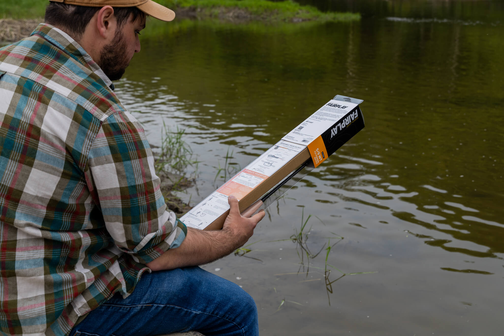 Angler with his back towards the camera as he reads the back packaging of a Cortland Line Rod