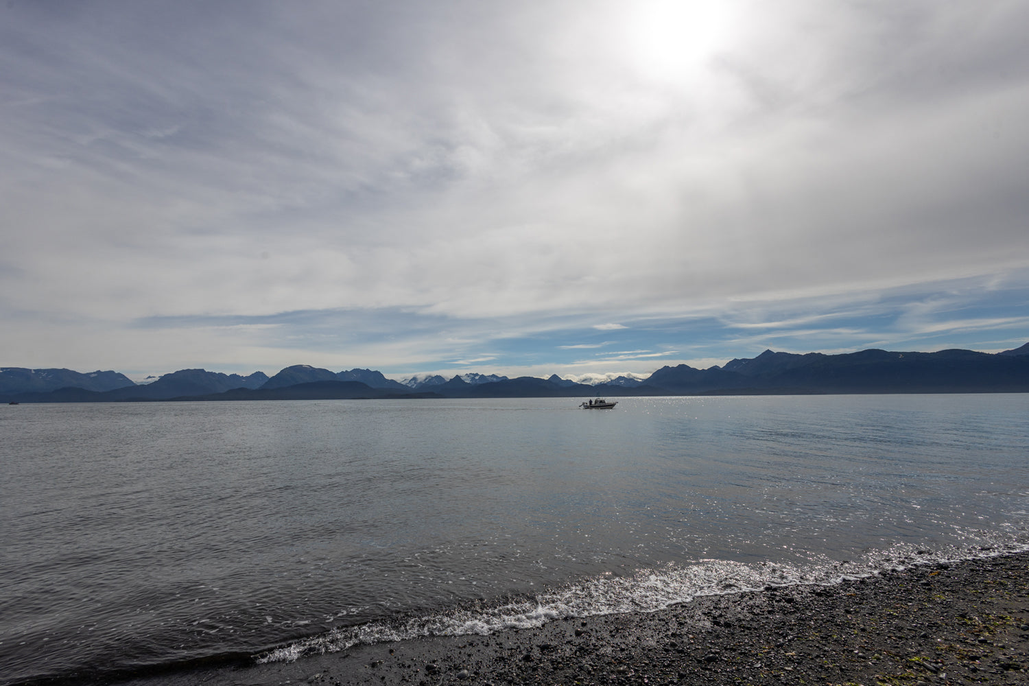 Landscape shot of mountains in the background, with a boat on a body of water.