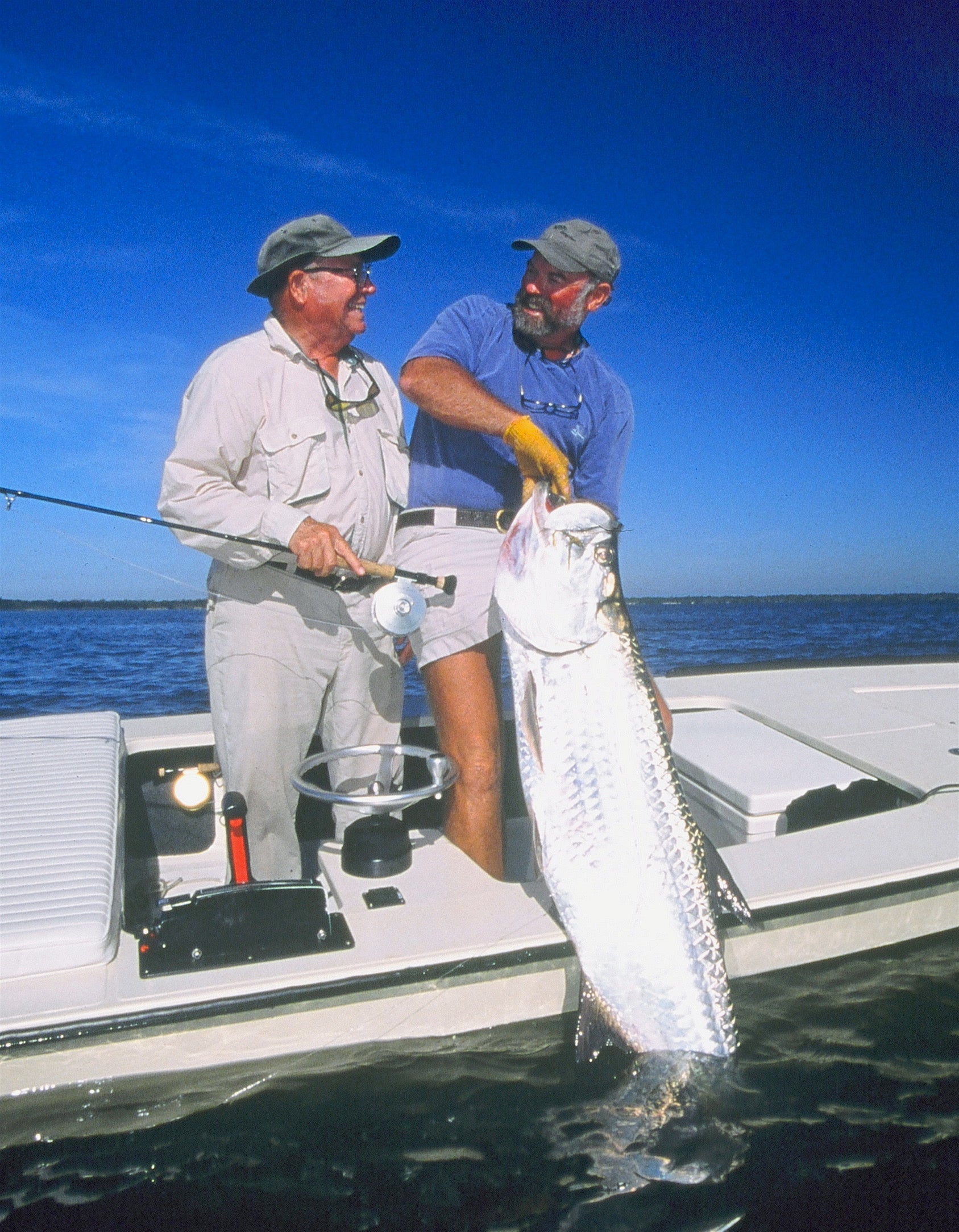 Flip Pallot and Lefty Kreh standing on a boat, while Flip is holding onto a large tarpon