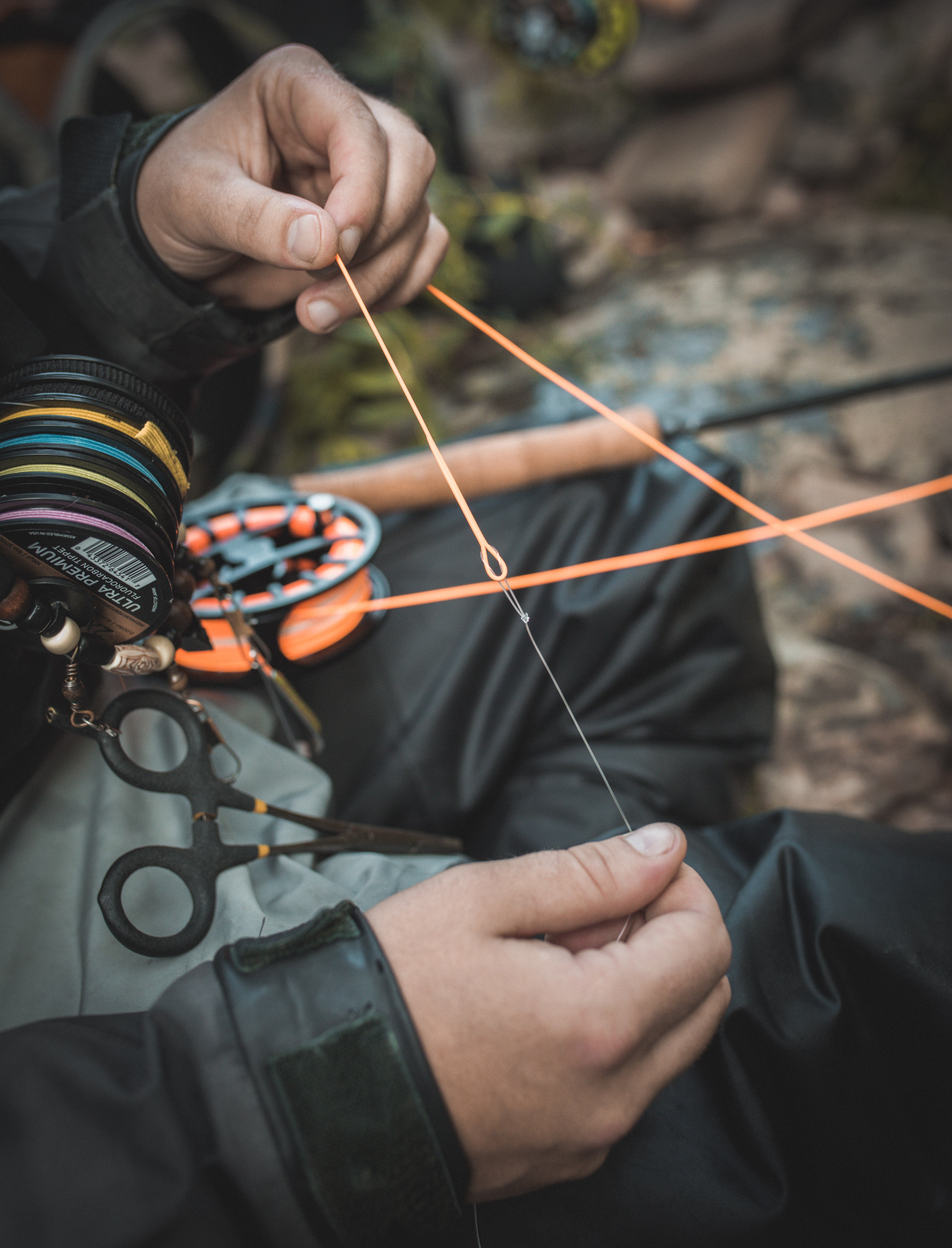 A set of hands are preparing their fly reel with line