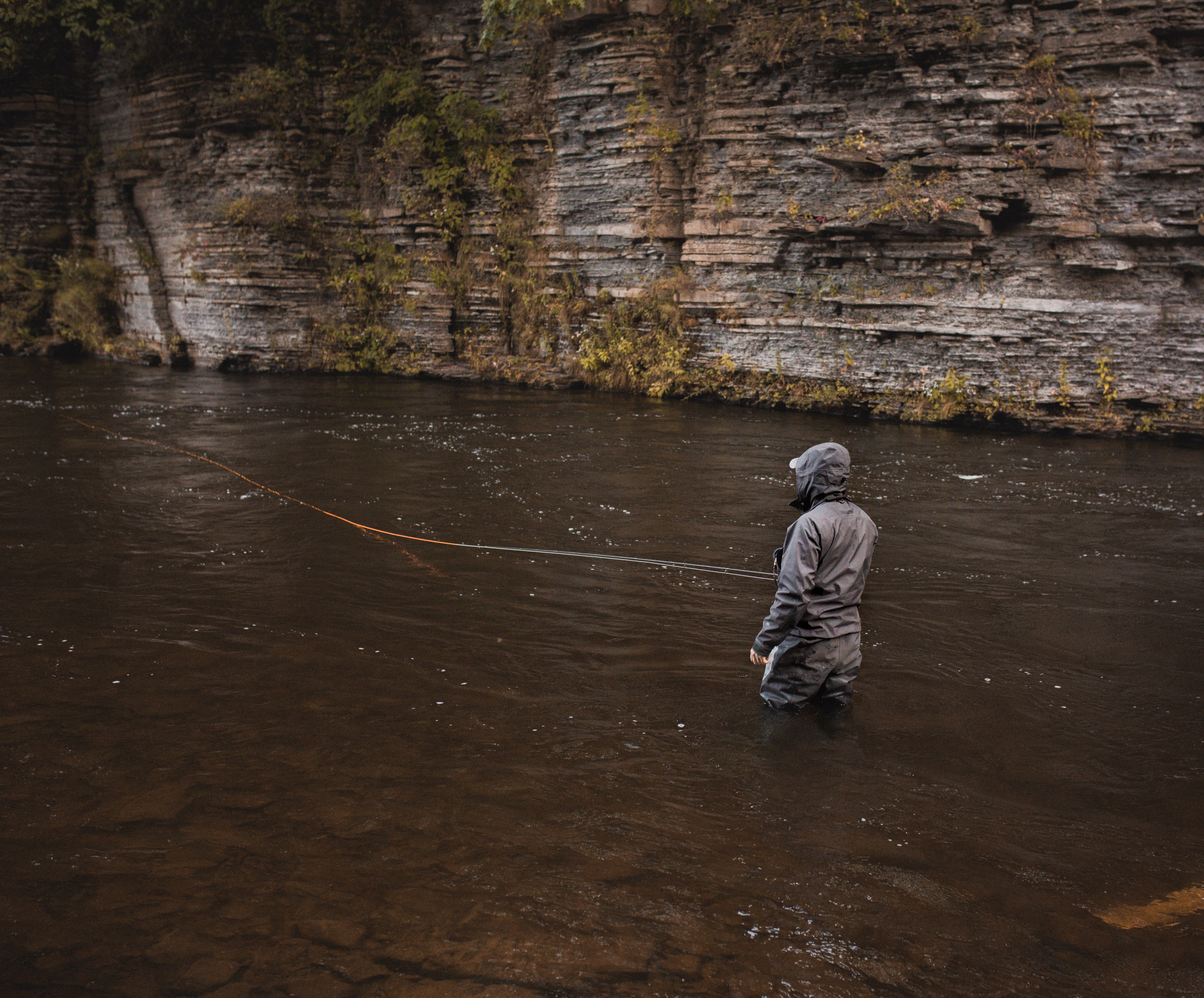 Ein Angler steht mit dem Rücken zur Kamera und seine Fliegenschnur liegt im Wasser