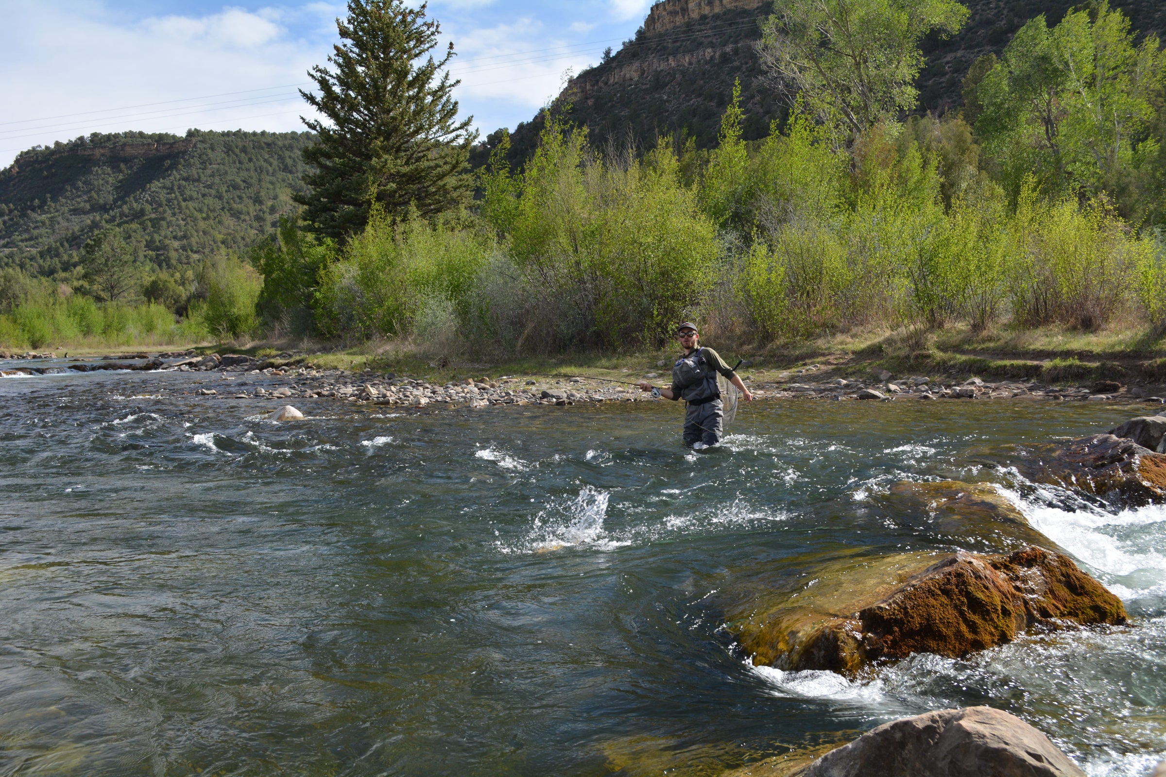Mann steht in einem Fluss beim Fliegenfischen