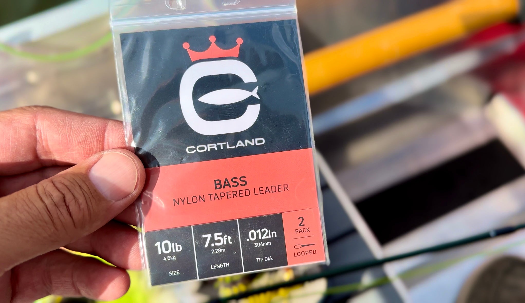 Primer plano del Bass Nylon Tapered Leader de Cortland en su embalaje. El embalaje tiene el logotipo de Cortland y es negro y rojo.