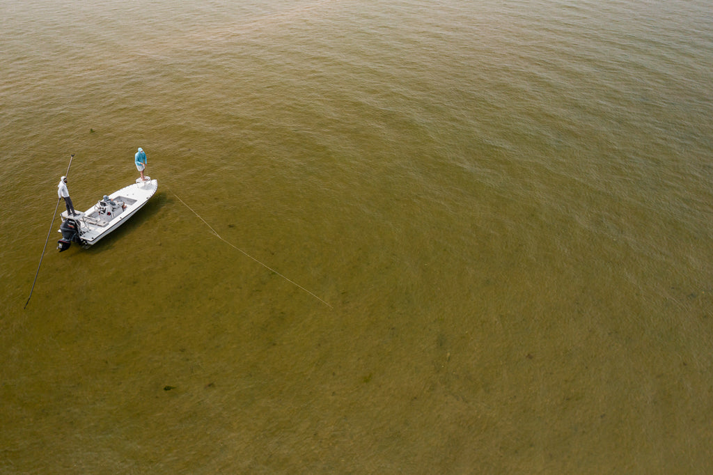 Two individuals flat fishing off a boat