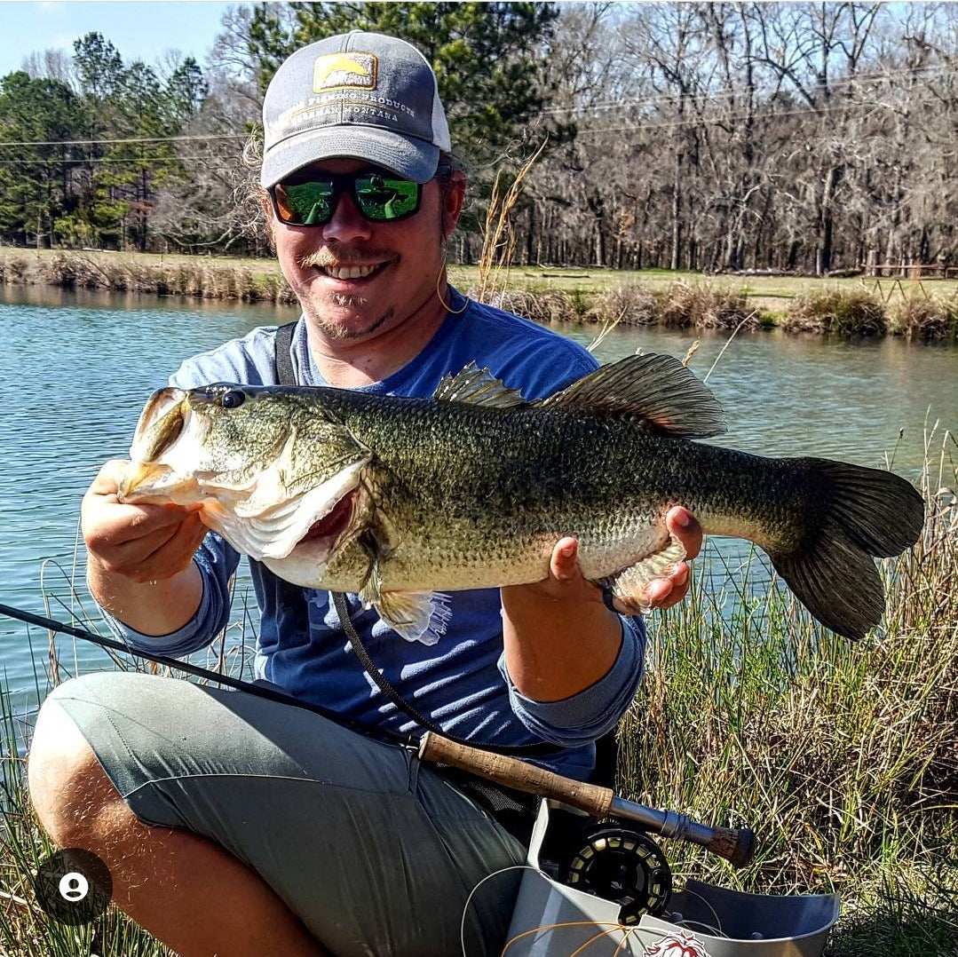 Pescador con su caña de pescar con mosca y la lubina que atrapó