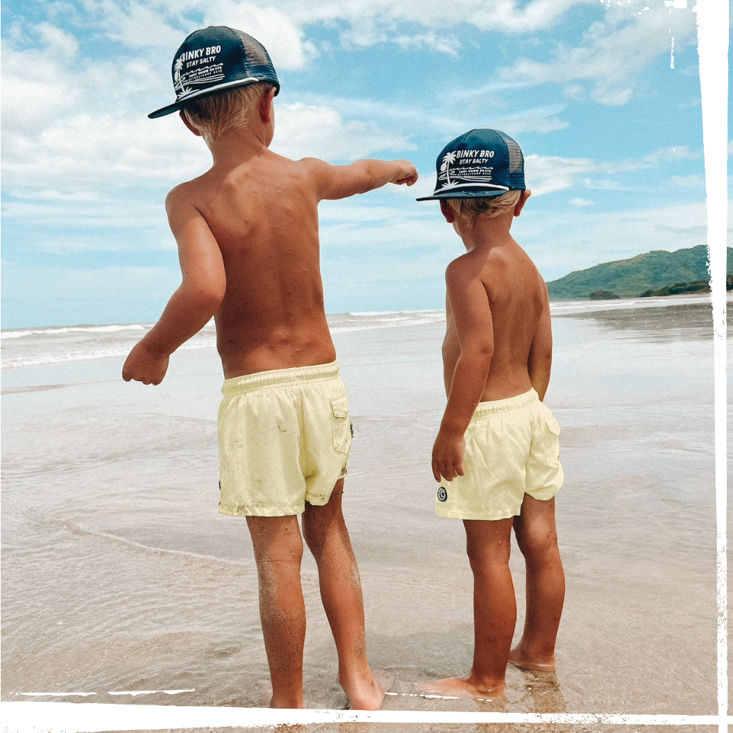 toddler wearing binkybro swimsuit and snapback at the beach