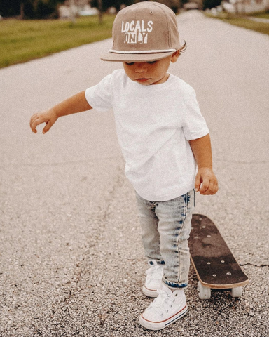 baby wearing a binkybro snapback next to skateboard