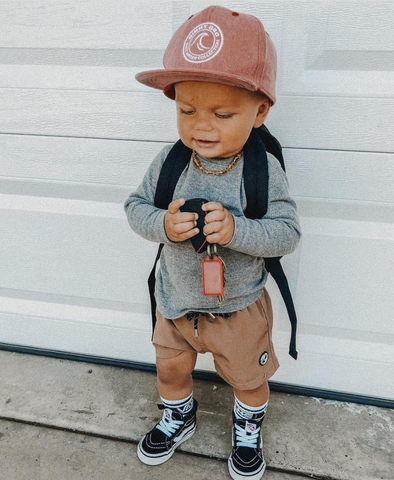 baby wearing vans and backpack and a binkybro beanie