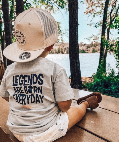 baby sitting facing away wearing binkybro snapback and t-shirt