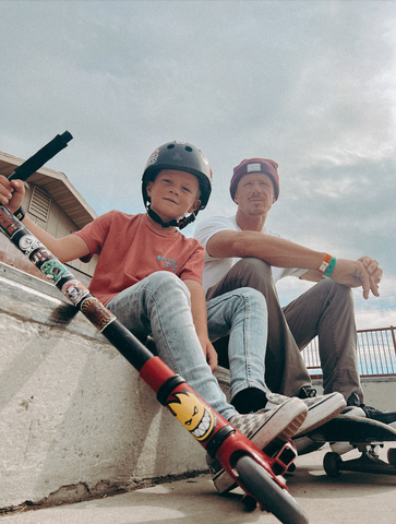 son with a helmet and binkybro stickers and father with binkybro beanie sitting on steps