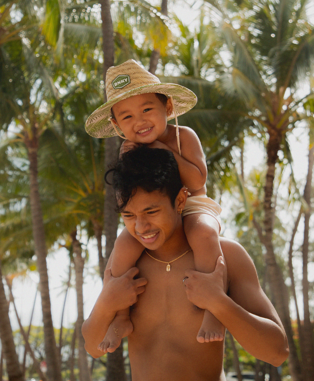 baby boy on dad's shoulders wearing binkybro barney patrol sun hat