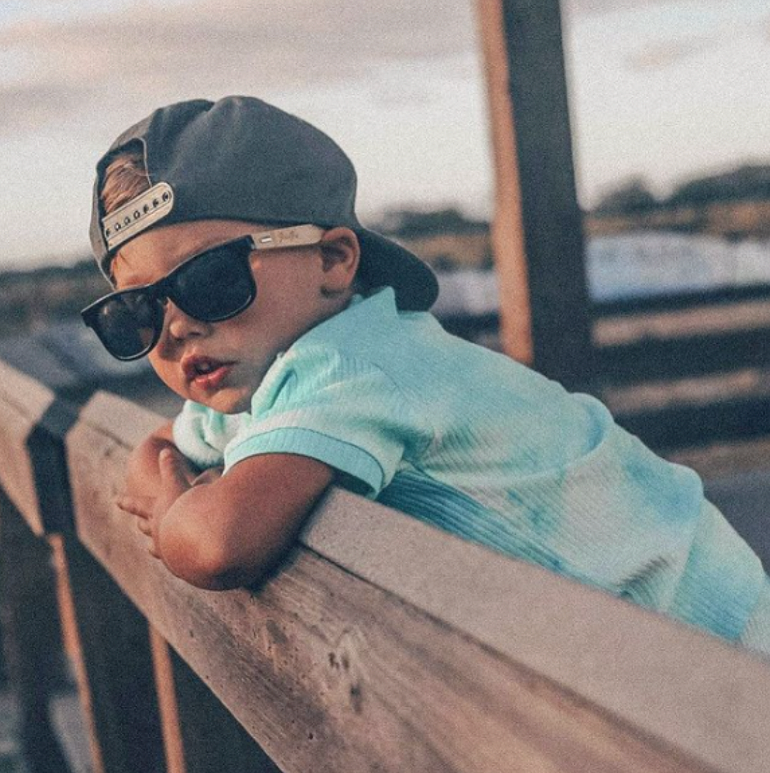 baby with binkybro sunglasses and snapback leaning over edge