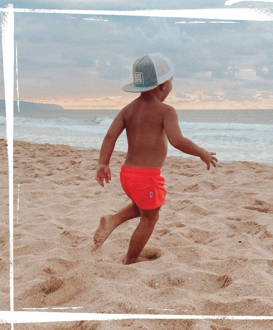 baby running on the beach in orange binkybro swimsuit