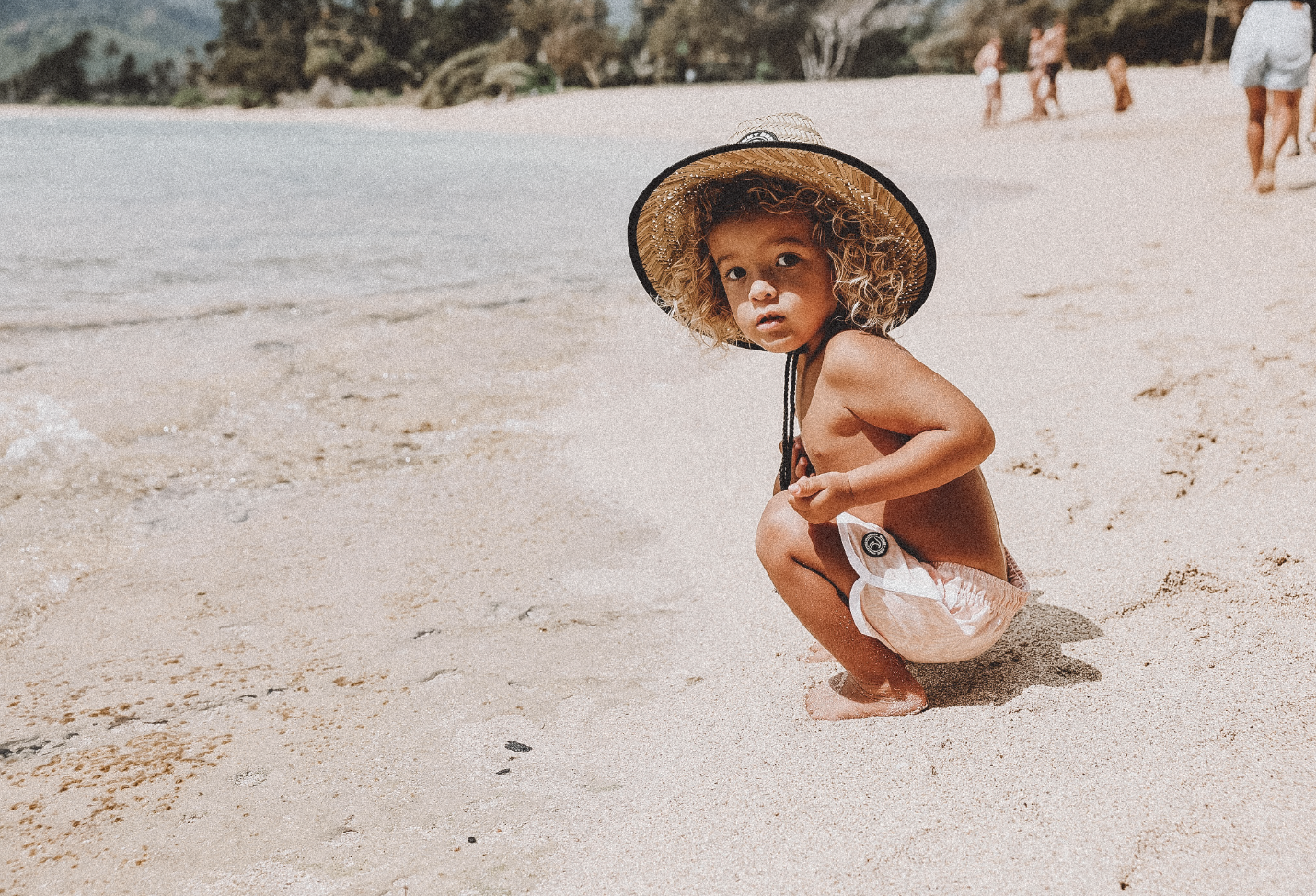 toddler at the beach wearing binky bro barney patrol sun hat