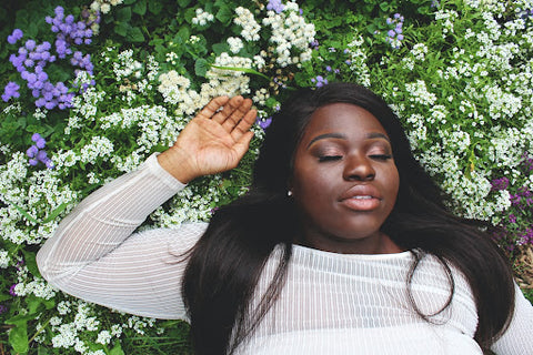 A person lying in flowers with their eyes closed.