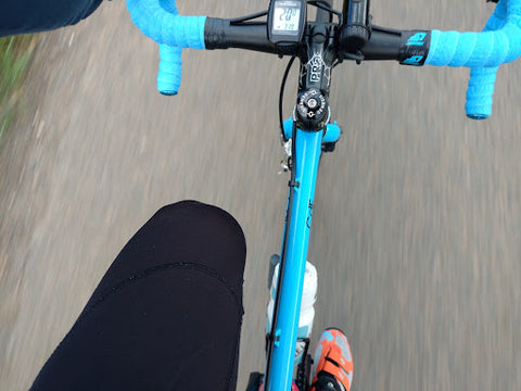 A woman wearing anti-chafing boxer briefs is riding a blue bicycle.