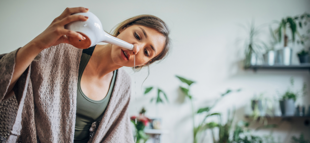 Woman using a neti pot to clean out her nasal cavity 