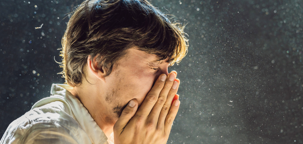 Image of man sneezing from dust particulates in the air