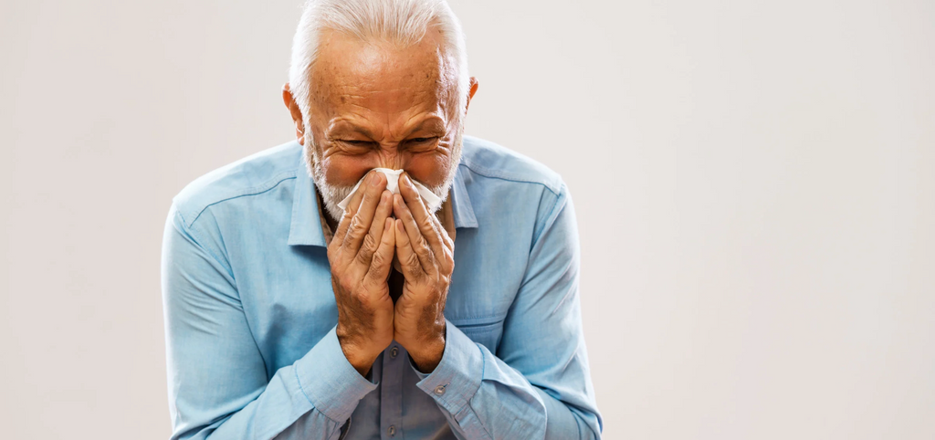 Image of elderly man sneezing from allergies