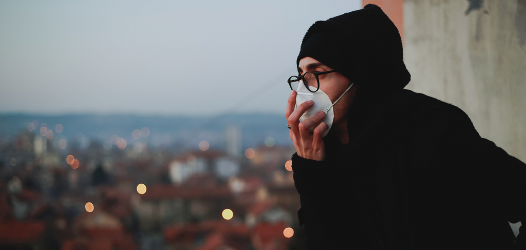 Image of a man wearing a face mask overlooking a city