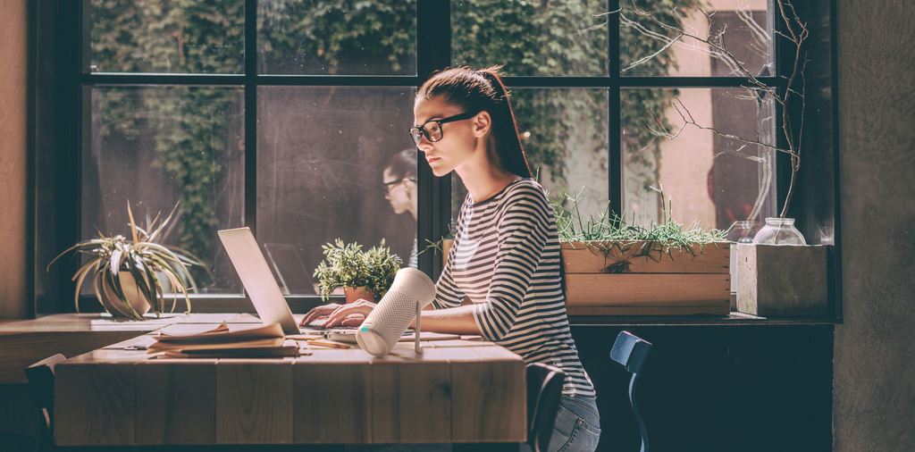 Image of woman sitting at desk using a WYND Plus Personal Air Purifier 