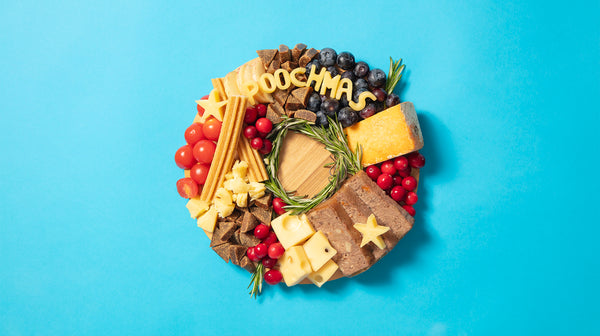 A pooch inspired cheeseboard with dog meat, dental sticks, and other treats, alongside cheese spelling out "Poochmas"