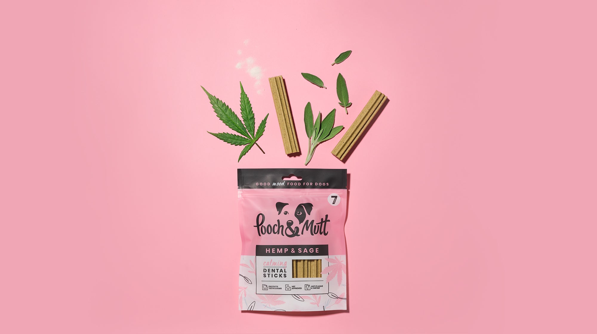 Our Pooch & Mutt Calming Dental Sticks packet, with ingredients and sticks bursting out, against a pale pink background