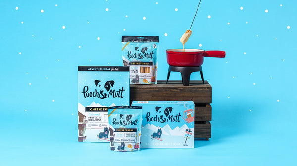 Our Pooch & Mutt ski-sonal Christmas Range with Cheese Fondue flavoured products, next to a Cheese Fondue pot, against a pale blue background