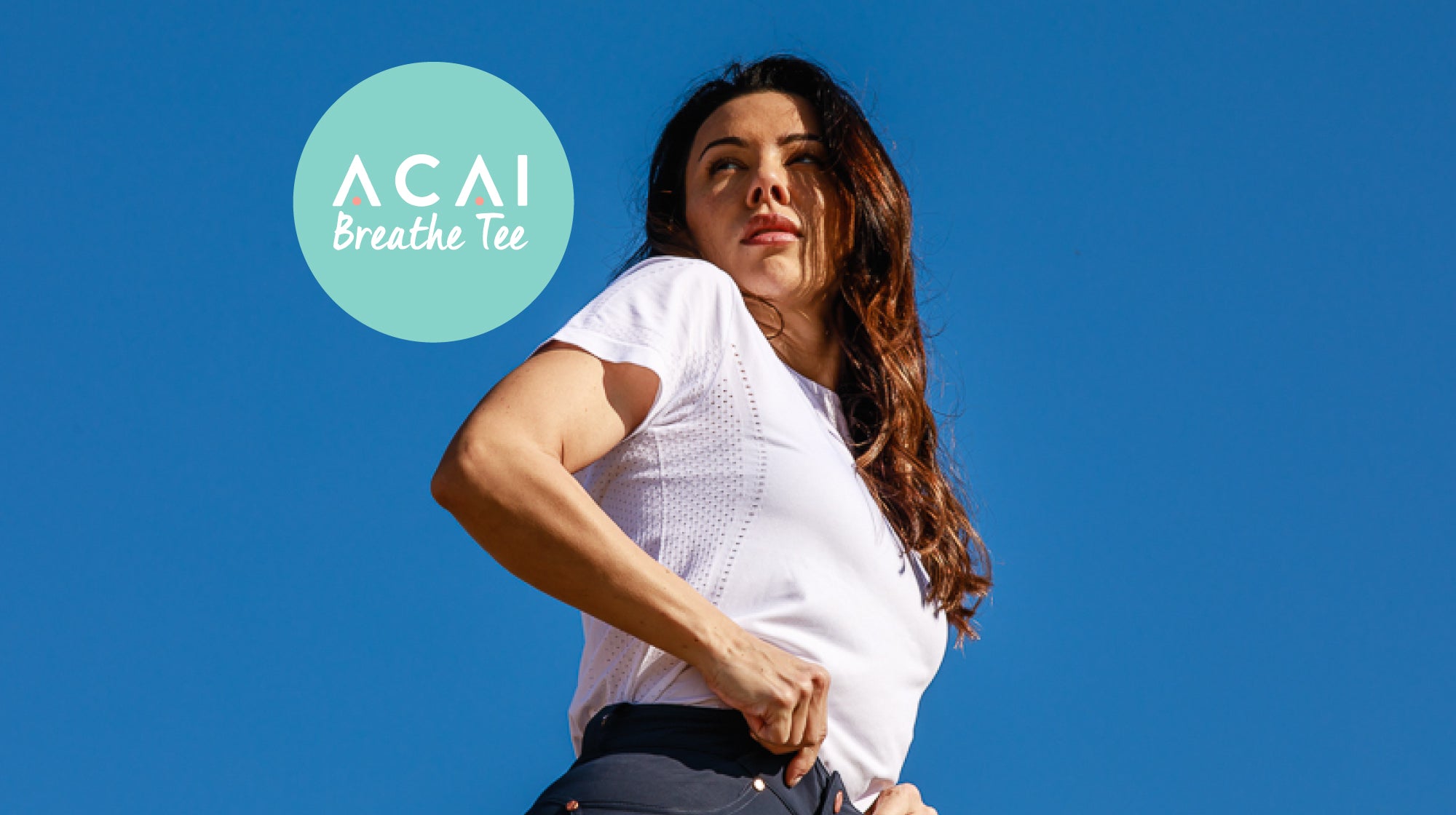 Woman outdoors against a blue sky, wearing a white Breathable Tee from ACAI