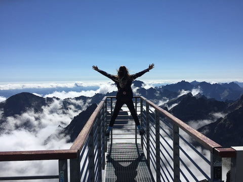 woman standing before mountains with arms stretched