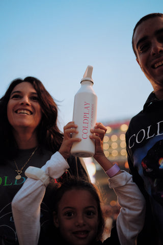 Two adults and a child at Coldpay concert holding customized MiiR Wide Mouth Bottle