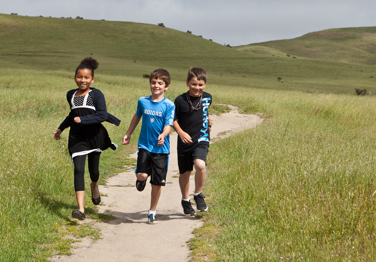 Children running down path surrounded by beautiful natural field lands