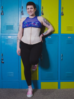 woman in latex waist cincher in front of school lockers