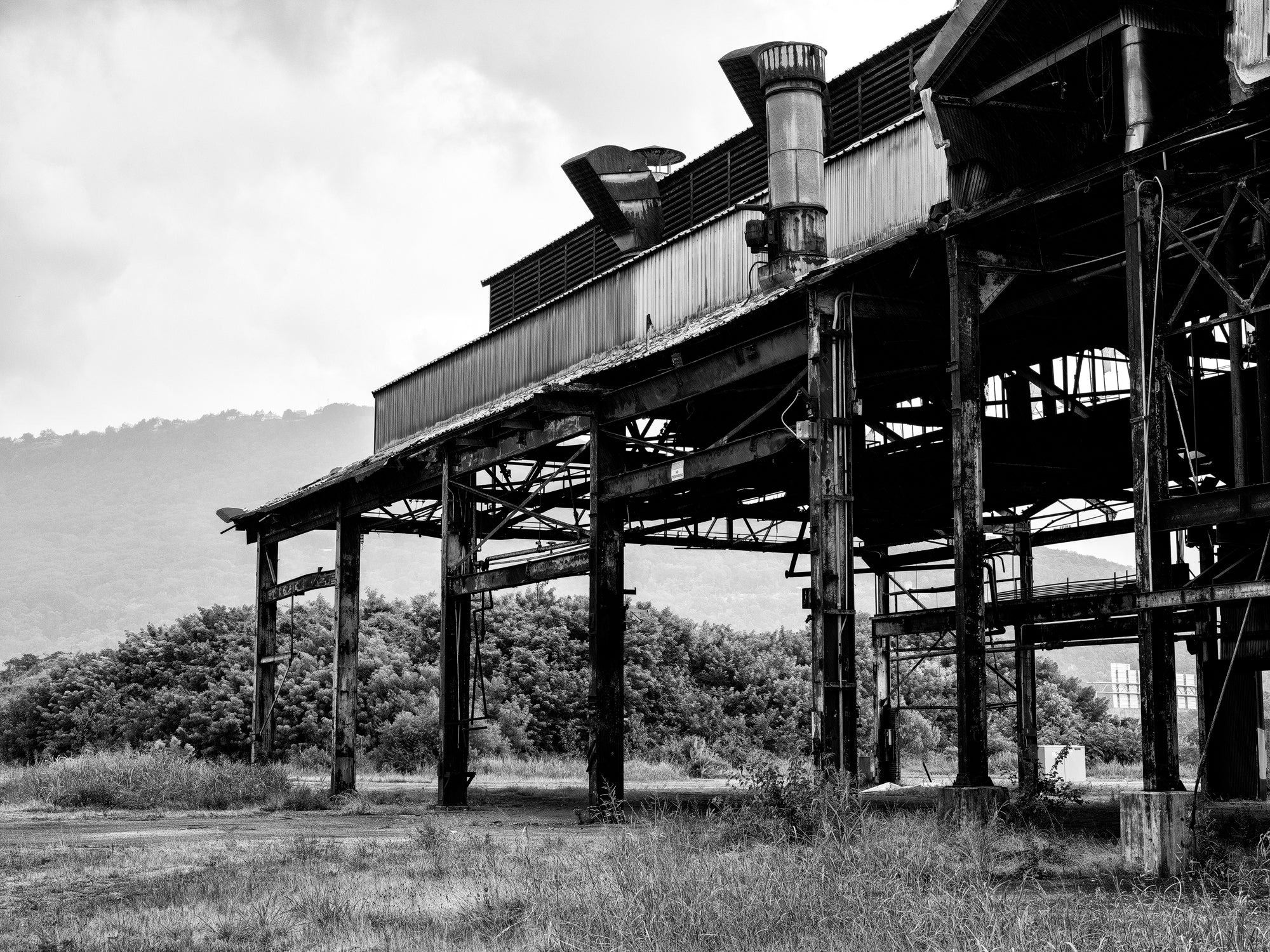 Black and white medium format photograph of the ruins of the vast abandoned Wheland Foundry in Chattanooga with a misty mountain in the distance.