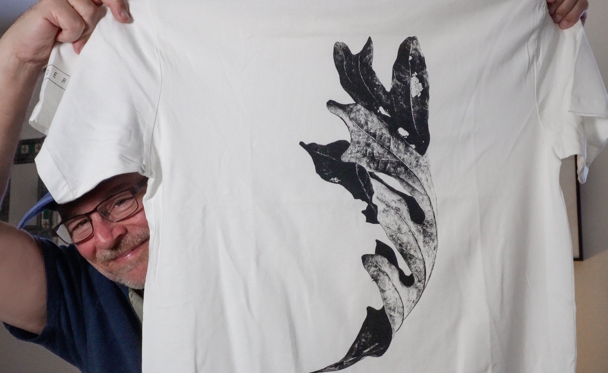 Photograph of Keith Dotson holding up the MADERA t-shirt featuring his Curled Autumn Leaf photograph