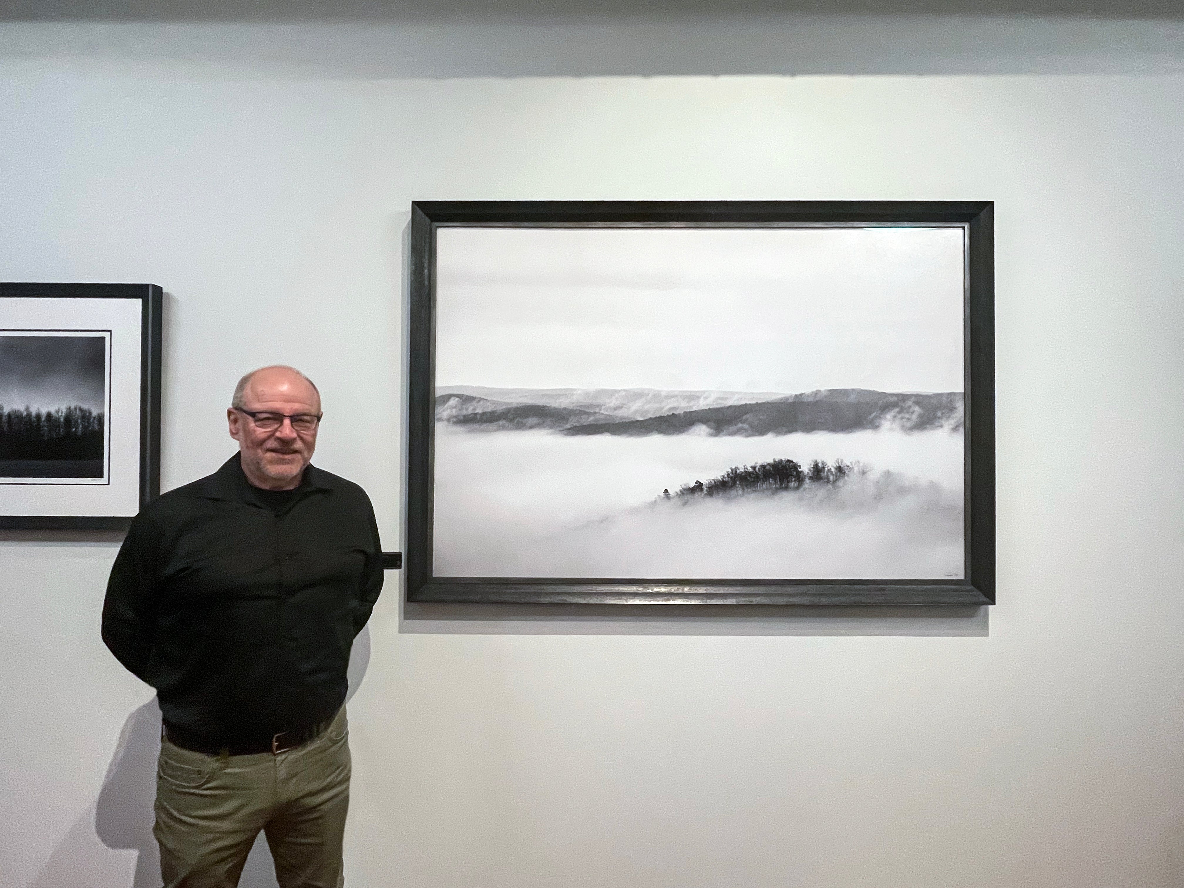 Nashville-based fine art photographer Keith Dotson pictured beside a 40 x 60-inch print of his foggy mountain landscape shot in North Carolina