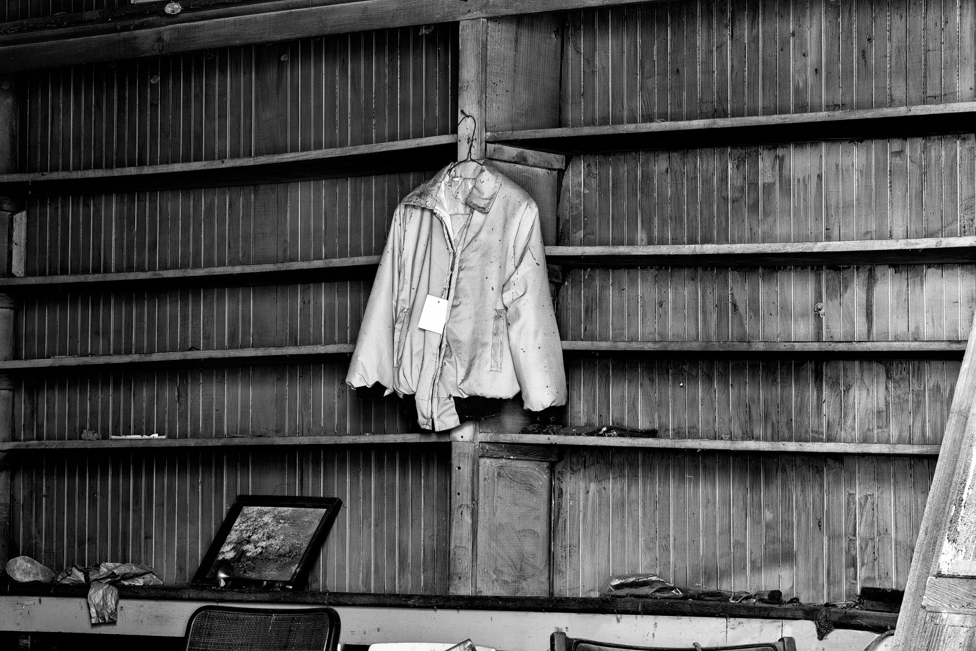 Blue Jacket with Sale Tag Hanging in an Abandoned Old Country Store - Black and White Photograph by Keith Dotson. Buy a fine art print.