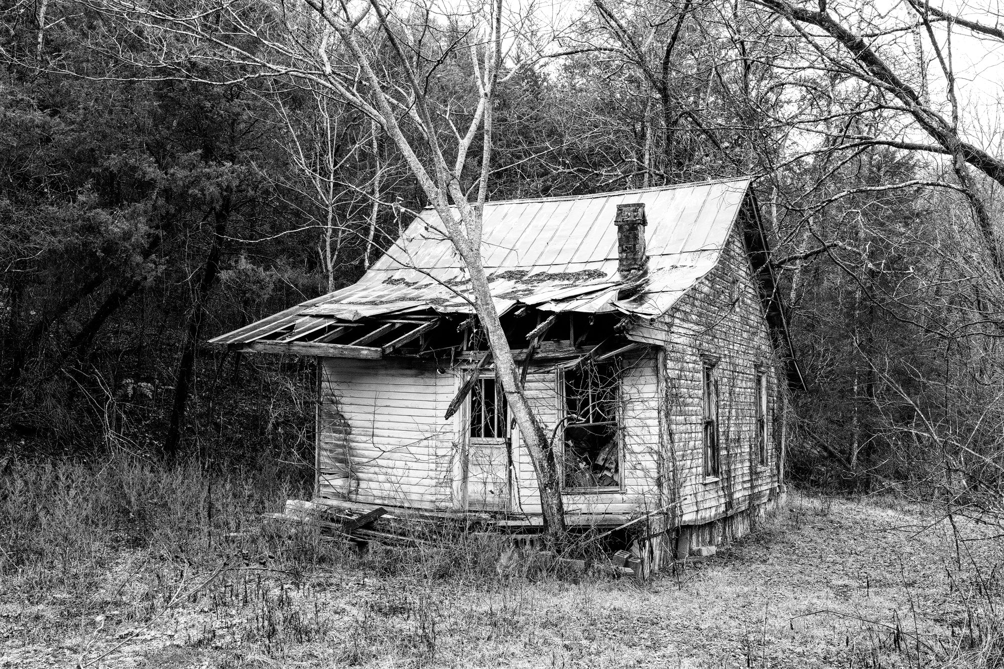 Black and white photograph of an abandoned rural farm house in the American South