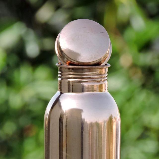 Copper H2O copper water bottle smooth brushed copper water bottle upper half blurry background