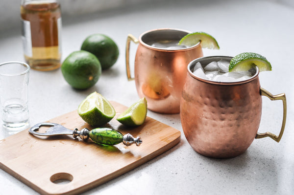 two Moscow Muled copper mugs filled with liquid ice lime wedges