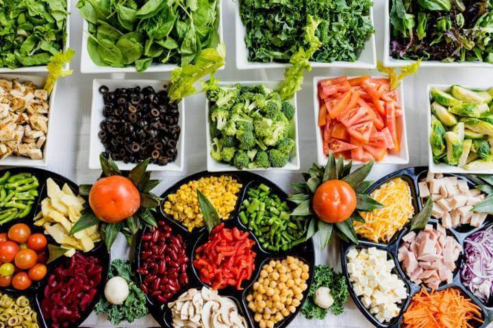 different types of fruits and vegetables placed on white square and black round plates