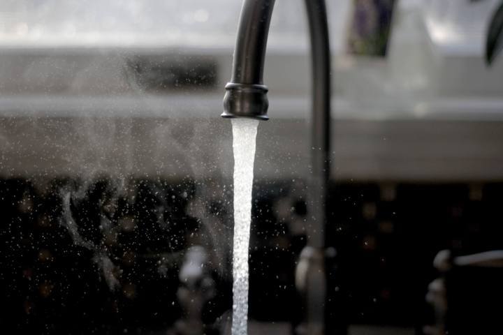 black faucet in sink water gushing out and misting