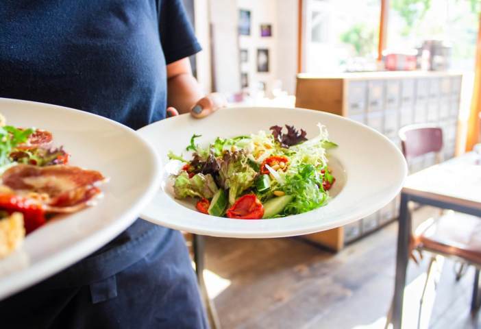 person carrying two round plates filled with vegetables salad