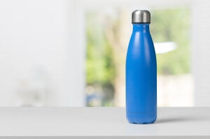 metal blue water bottle with silver cap placed on gray surface