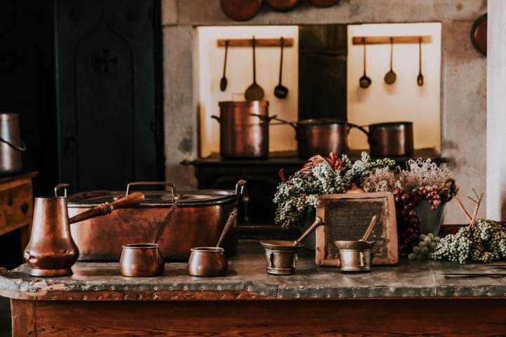 many pieces of different types of copper vessels in a kitchen setting