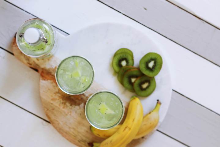 two glasses and bottle filled with water and kiwi slices top view